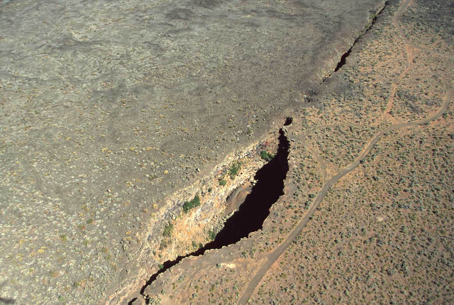 Kings Bowl and Great Rift from air. King's Bowl is a phreatic explosion pit 280 feet (85 m) long, 100 feet (30 m) wide, and 100 feet (30 m) deep, caused by lava coming in contact with groundwater producing a steam explosion 2,200 years ago. (NPS photo)
