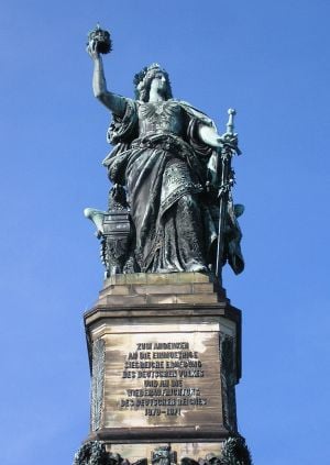 allegorical figure of Germania (woman with flowing robes, sword, flowing hair) standing, holding crown in right hand, sword partially sheathed