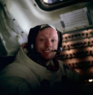 Armstrong smiling in his space suit with the helmet off. He wears a headset and his eyes look slightly watery.