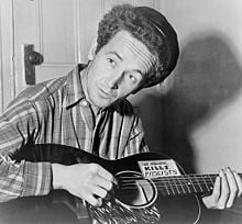 Woody Guthrie in 1943 with guitar labeled "This machine kills fascists"