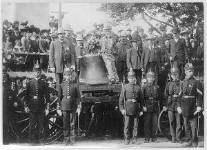 The Liberty Bell on a wagon, a number of people, including policemen, pose with it.