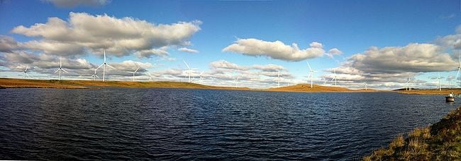 A panoramic view of the Whitelee Wind Farm with Lochgoin Reservoir in the foreground.