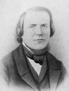 Head and bust of a man with a high forehead, hair reaching his shoulders, wearing a 19th-century three-piece suit and a cravat