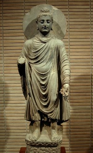 standing Buddha statue with draped garmet and halo