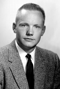 A black-and-white photo of a young man with light skin and pale irises. His mid-colored hair is cut short. He is looking at the camera. He is wearing a barleycorn sport coat, a white shirt and a dark necktie.
