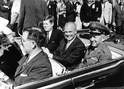 A smiling Glenn in the back seat of a limo with John F. Kennedy and General Leighton I. Davis
